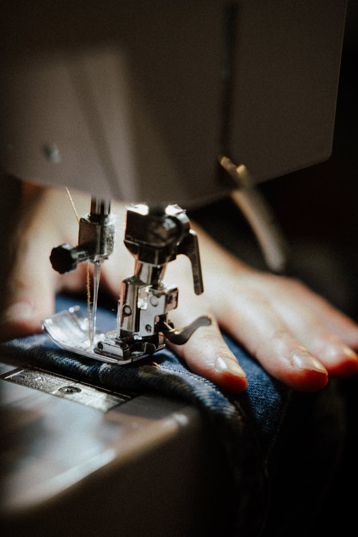 Detailed view of a sewing machine in use with a focus on denim material. Ideal for textile industry insights.