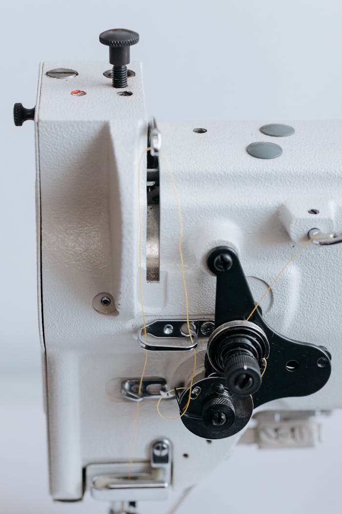 Detailed view of industrial sewing machine components showcasing mechanical parts and threads.